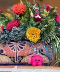 Piggy bank in front of colorful flowers in a ceramic pot