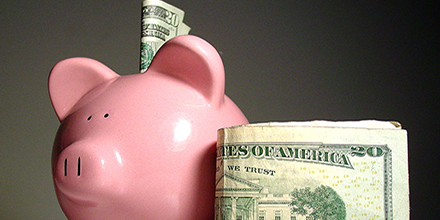 Piggy bank with twenty dollar bills next to it.