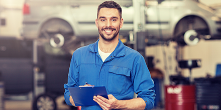 Man holding clipboard smiling in front of car shop