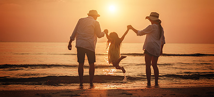 Family playing at beach enjoying the sunset.