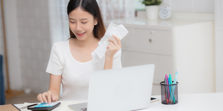 Woman calculating bills in front of laptop