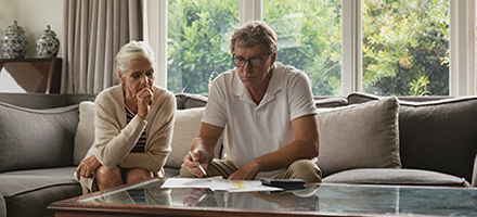 Middle aged couple sitting in living room analyzing their finances.