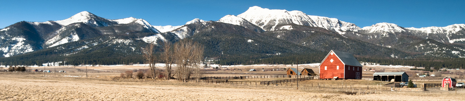 Snowy mountains behind red barn and farm