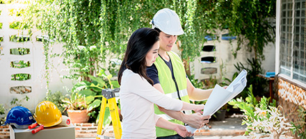 Woman and Man looking at blueprints near a home