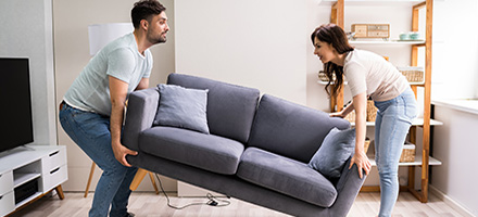 Young couple moving a new couch into their home.