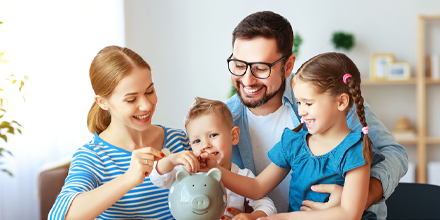 Happy family in living room putting coins into piggy bank