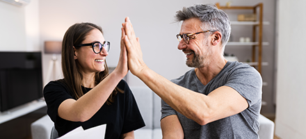 Middle aged couple high fiving each other. 