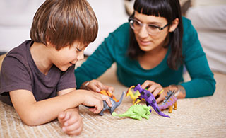 Mom and son playing with dinosaurs on floor